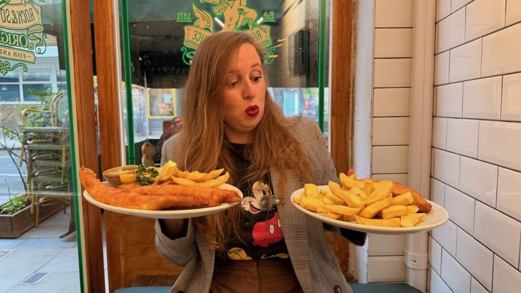 Elena de Orangepassport con dos platos de fish and chips en un restaurante de Londres